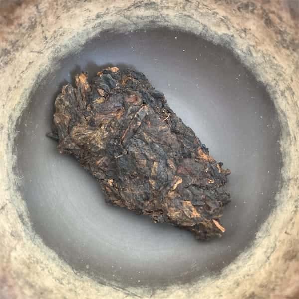 a chunk of leaves from the brick, gold and dark brown in color, sitting in a brown gaiwan