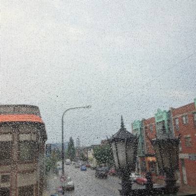 The album cover for 2. It is a photo, out the window of my apartment, looking out on to Elmwood Avenue in Buffalo New York. You can see a lamp post, with two lamps, and buildings to the right and left. The focus of the image is actually on the window screen and the rain drops on it.