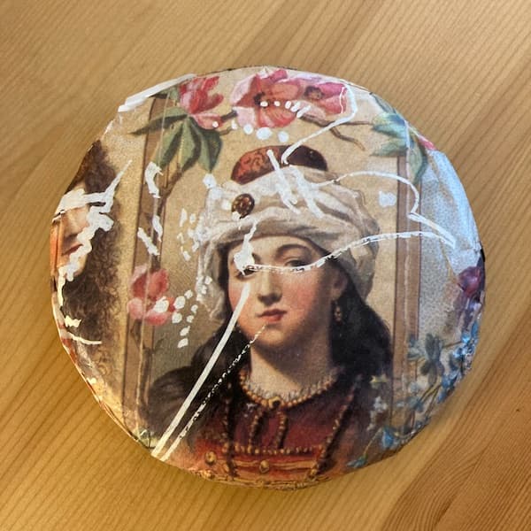 the compressed tea cake in it's wrapper, a painting of middle eastern princess surrounded by flowers