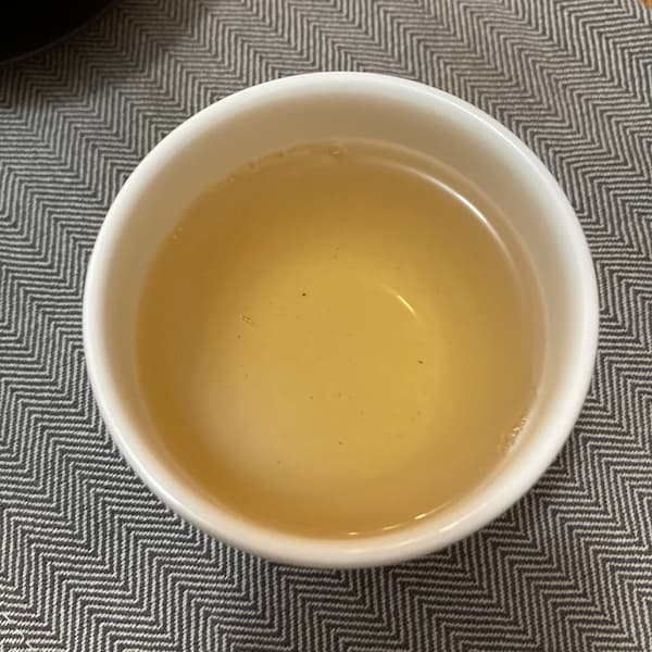 the tea, amber in color, in a small white cup
