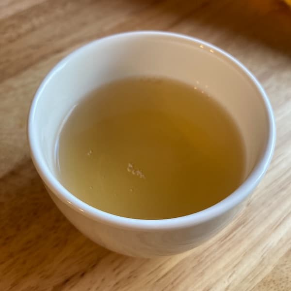 the tea, light yellow in color, in a small white cup