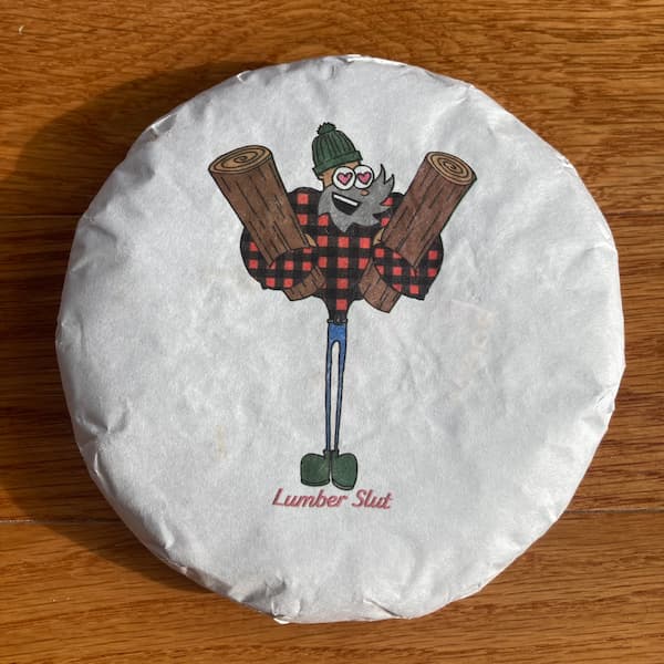 the compressed tea cake in it's white paper, on the wrapper there is a cartoon lumberjack holding to logs with hearts in his eyes