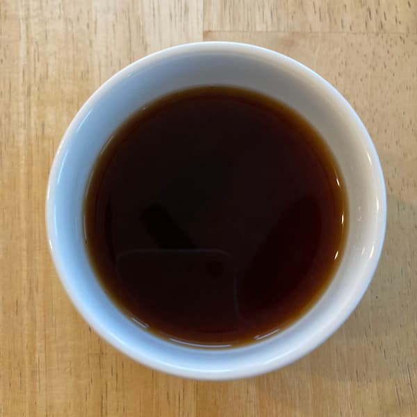 the tea, dark brown in color, in a small white cup