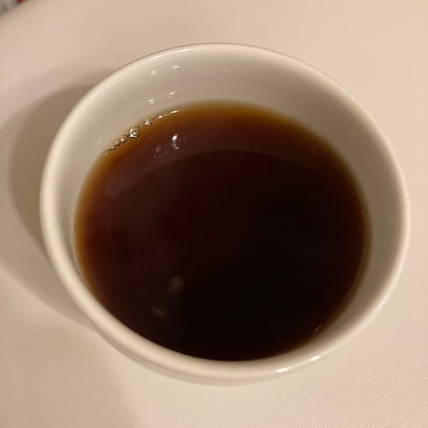 the tea, dark brown in color, in a small white cup