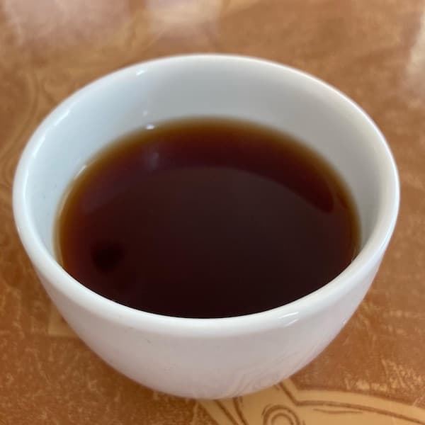 the tea, brown in color, in a small white cup