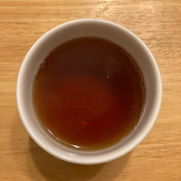 the tea, amber in color, in a small white cup