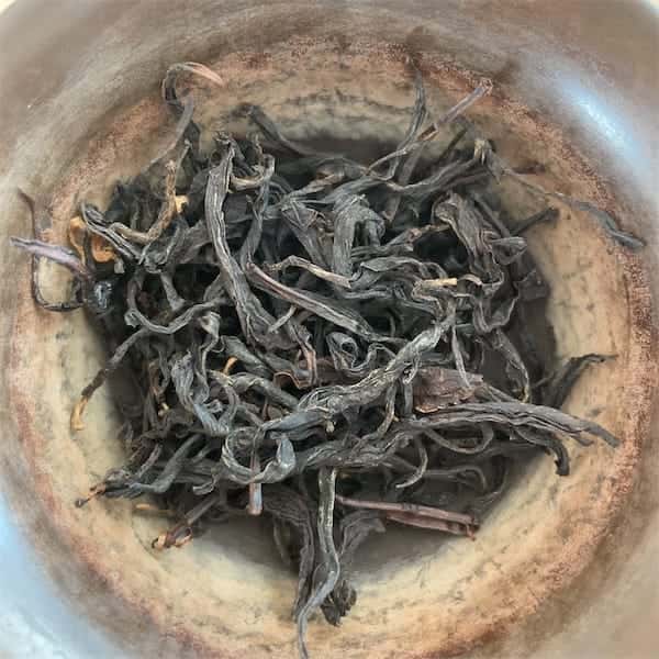 the twisted dark gray and brown leaves in a brown gaiwan