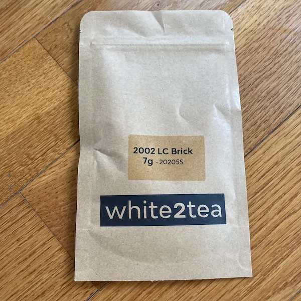 A tan colored mylar package with the words 2002 LC Brick 7g - 202025 white2tea displayed on it