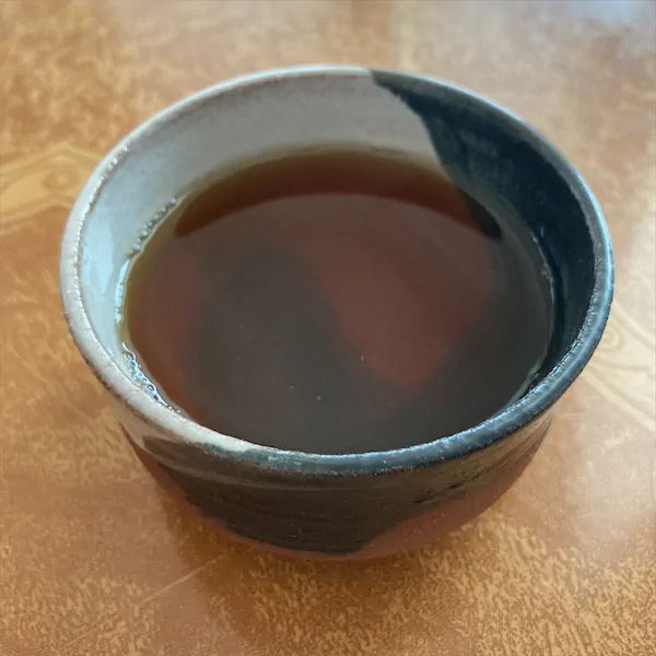 the tea, caramel in color in a multi colored ceramic cup