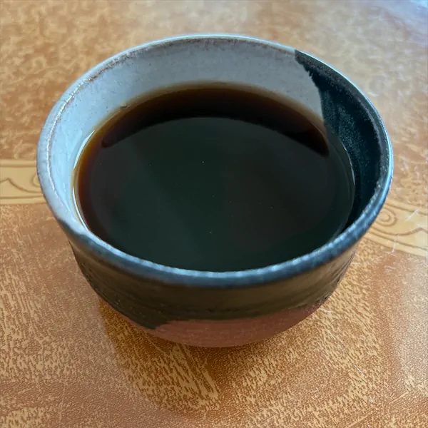 the tea, dark in color in a multi colored ceramic cup