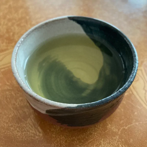 the tea, very light green to yellow in color, in a multi colored ceramic cup