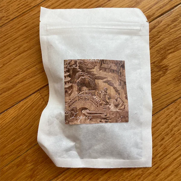 a white mylar package with a decorative stylized label showing two people at the foot of a small bridge