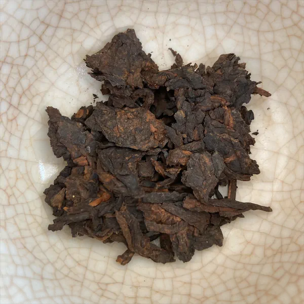 the tea, dark brown and tan colored leaves, in a white porcelain gaiwan