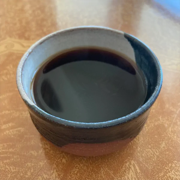 the tea, dark caramel in color, in a multi colored ceramic cup