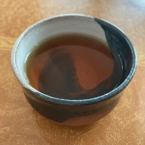 the tea, caramel in color, in a multi colored ceramic cup