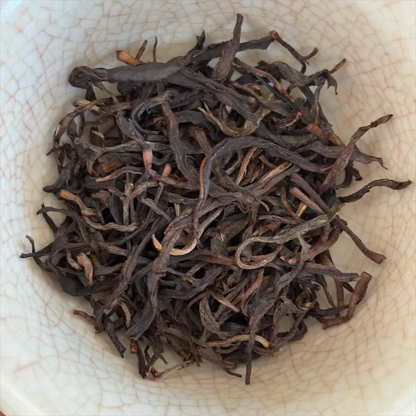 dark brown, grayish brown, and tan colored leaves in a white porcelain gaiwan