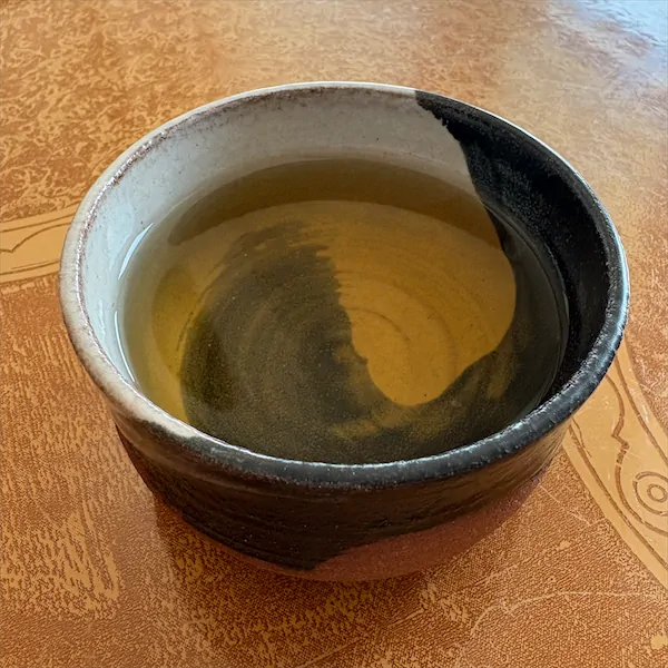 the tea, very light brown in color, in a multi colored ceramic cup